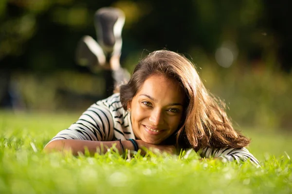美丽的年轻女子躺在公园的草地上笑着的正面画像 — 图库照片