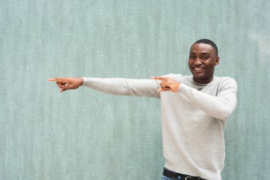 Yeşil duvarı işaret eden gülümseyen siyah adamın portresi 