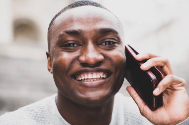 Akıllı telefonla konuşan mutlu Afrikalı Amerikalı adamın portresini kapat.