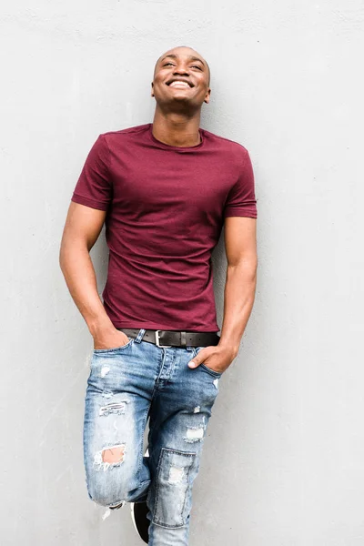 Portrait Happy Young Man Leaning Gray Wall Hands Pockets Looking — Stock Photo, Image