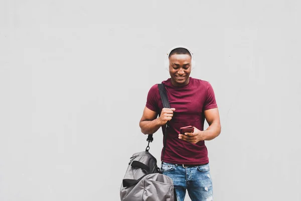 Porträtt Leende Afroamerikansk Man Med Väska Och Mobiltelefon Vid Grå — Stockfoto