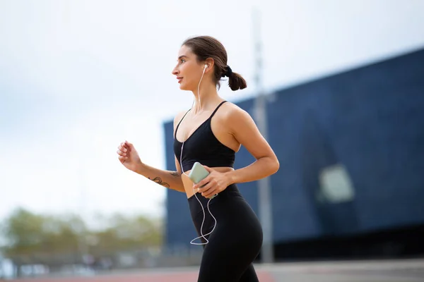 Seitenporträt Einer Sportlerin Mit Kopfhörern Und Handy Die Morgens Draußen — Stockfoto