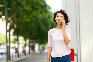 Şehirde cep telefonuyla konuşan çekici genç bir kadın.