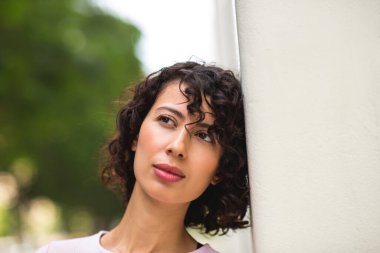 Güzel genç bir kadın duvara yaslanıyor ve düşüncelerine bakıyor.