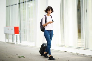 Kadın gezgin, şehirdeki cep telefonundan bavul ve kısa mesaj çekiyor.