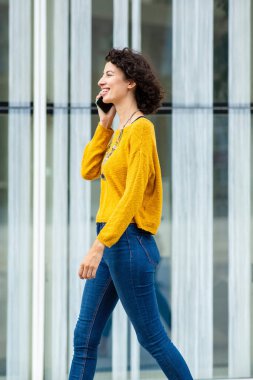 Şehirde yürürken cep telefonuyla konuşan mutlu Arap kadın profili