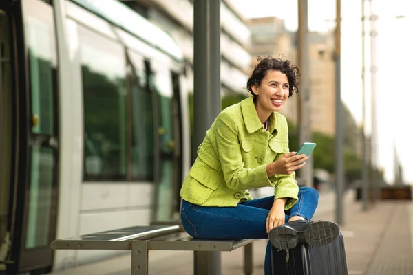 Uśmiechnięta Kobieta Korzystająca Telefonu Komórkowego Podczas Oczekiwania Przystanku Autobusowym Mieście — Zdjęcie stockowe