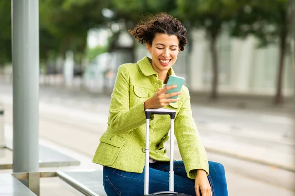 Szczęśliwa Kobieta Podróżujący Pomocą Telefonu Komórkowego Podczas Oczekiwania Przystanku Autobusowego — Zdjęcie stockowe