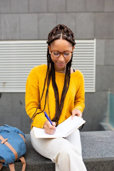 Πορτρέτο Της Αφρικανικής Φοιτήτριας Κάθεται Έξω Γράφοντας Ένα Βιβλίο — Φωτογραφία Αρχείου