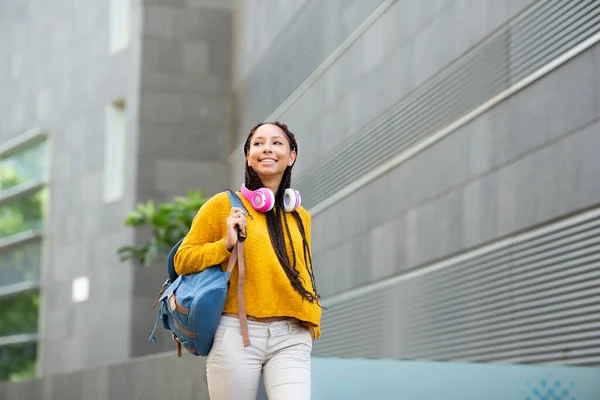 街でバッグやヘッドフォンで歩くかなり若い黒の女の子の肖像画 — ストック写真