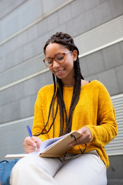 Dışarıda oturan gülümseyen öğrencinin portresi not defterine not alıyor.