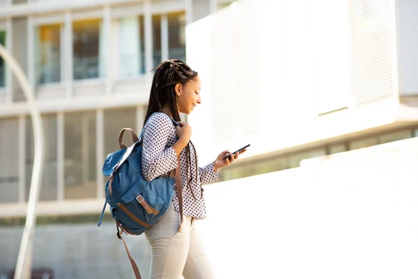 Şehirde Yürürken Çantasıyla Cep Telefonuyla Mesajlaşan Mutlu Zenci Kız Öğrencinin — Stok fotoğraf