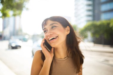 Şehirde telefonla konuşan güzel, gülümseyen genç bir kadının portresini yakından çek.