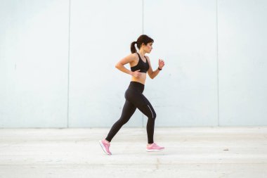 Spor giyimli aktif bir kadının sabah dışarıda koşarkenki portresi.