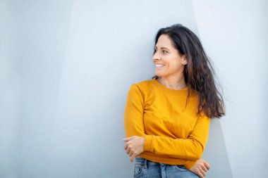 Kollarını kavuşturmuş güzel, beyaz bir kadın yan tarafa bakıyor.