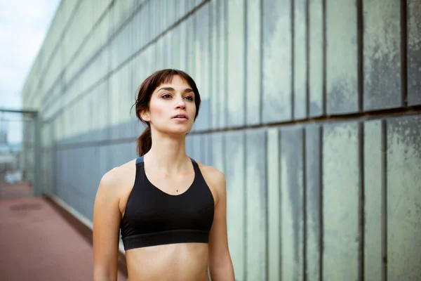 Portrait of fit young woman in sports wear standing outdoors after exercises