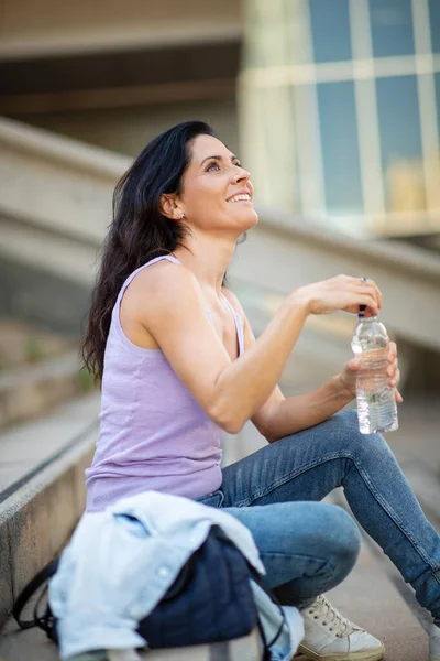 Mujer Alegre Mirando Hacia Arriba Mientras Sienta Con Botella Agua —  Fotos de Stock