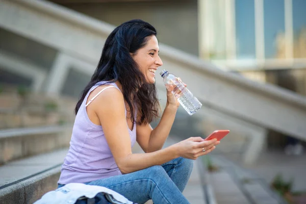 Mujer Divirtiéndose Mientras Bebe Agua Mensajería Teléfono Móvil Aire Libre —  Fotos de Stock