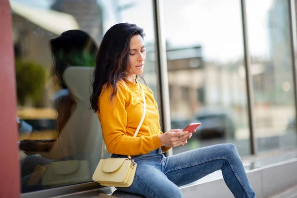 Mulher Elegante Jeans Casuais Mensagens Topo Usando Telefone Celular Enquanto — Fotografia de Stock