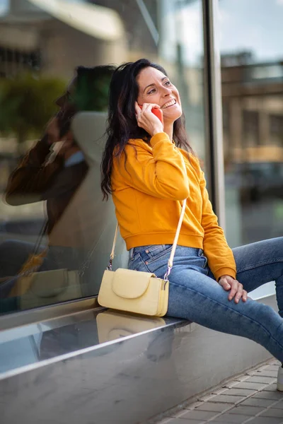都会でアウトドアをしながら携帯電話で話すスタイリッシュな成熟した女性 — ストック写真