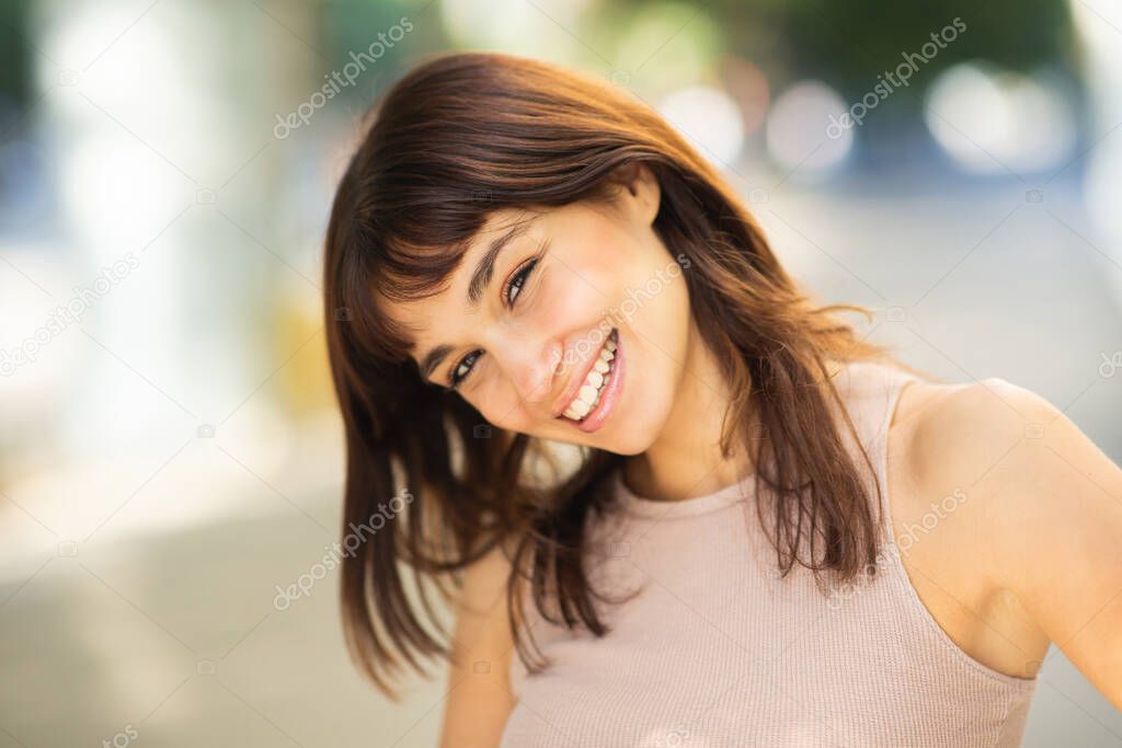 Close up portrait of elegant young woman looking at camera and smiling outside