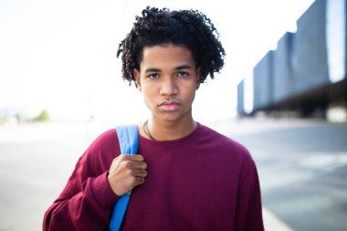 Şehirde sırt çantalı ciddi bir siyah adamın portresi.