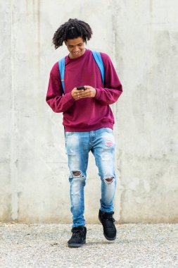 Mutlu Afro-Amerikan adam açık havada cep telefonu kullanarak mesajlaşıyor.