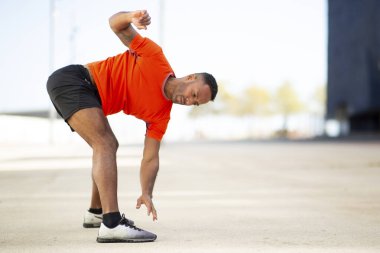 Genç sporcu şehirde koşmadan önce ısınıyor ve ısınıyor.