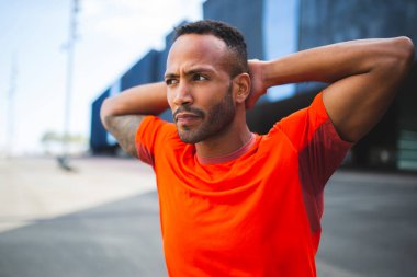 Adam ısınma egzersizi yaparken ellerini başının arkasında uzatıyor.
