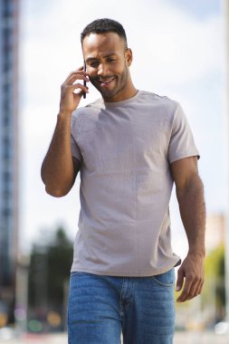 Şehirde cep telefonuyla konuşan mutlu genç adam.