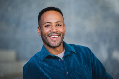 Mavi gömlekli, dost canlısı genç adamın portresi.