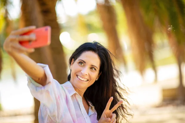 Веселая Женщина Жестикулирует Знаком Мира Делая Селфи Помощью Камеры Мобильного — стоковое фото