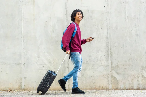 ハッピー男見上げながら携帯電話と引っ張っスーツケース屋外で市 — ストック写真