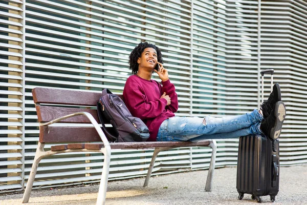 幸せな男は携帯電話で話をしながら検索し 荷物を持って街のベンチに座って — ストック写真
