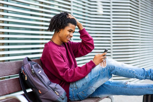 Glad Man Meddelanden Med Mobiltelefon Medan Sitter Med Ryggsäck Utomhus — Stockfoto