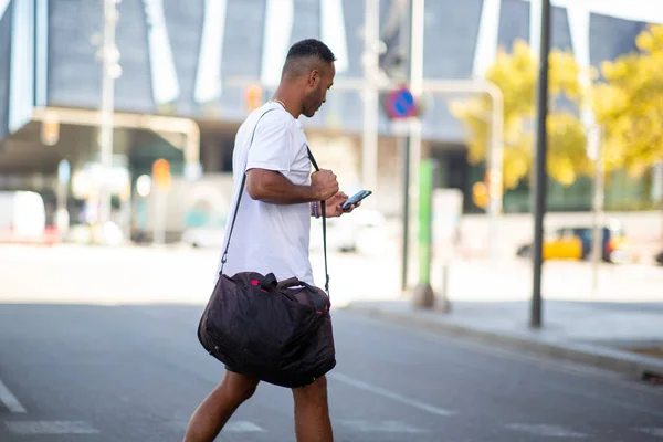 Muž Nesoucí Sportovní Tašku Při Používání Mobilního Telefonu Přecházení Přes — Stock fotografie