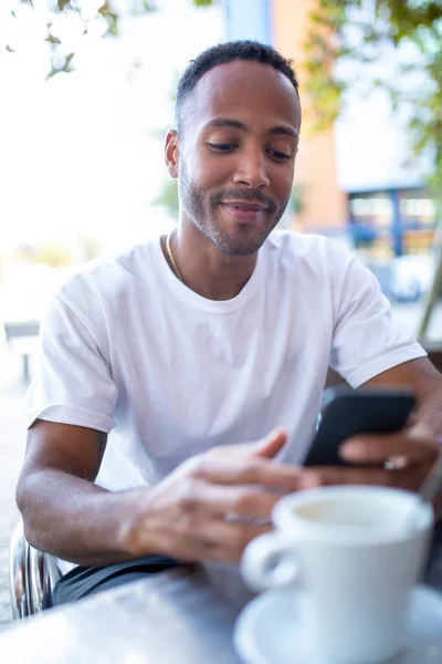 坐在咖啡店边 一边笑一边看手机短信的非洲裔美国人 — 图库照片