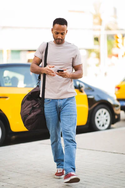 Przystojny Afroamerykanin Telefonem Komórkowym Torbą Świeżym Powietrzu Mieście — Zdjęcie stockowe