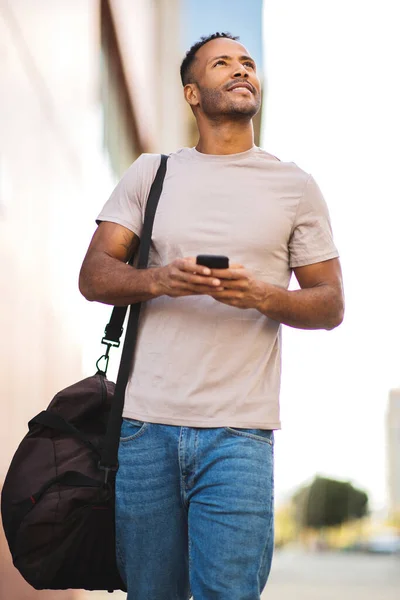 Glimlachende Afrikaans Amerikaanse Man Met Smartphone Tas Zoek Naar Buiten — Stockfoto