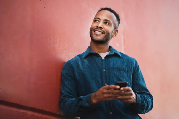 Uśmiechnięty Afroamerykanin Spoglądający Górę Podczas Korzystania Telefonu Komórkowego Zewnątrz Mieście — Zdjęcie stockowe