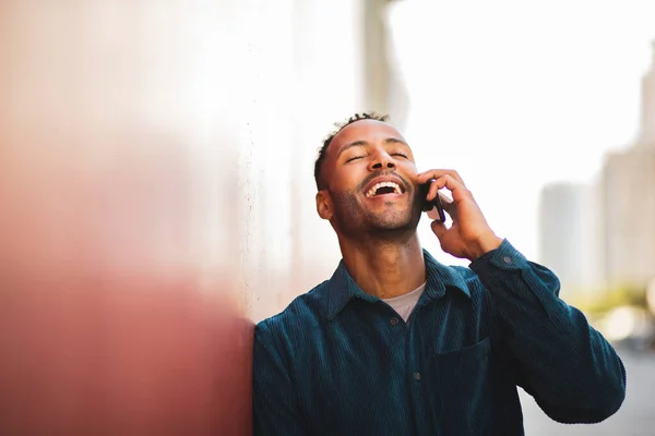 stock image Joyful man laughing while talking on mobile phone outdoors in city