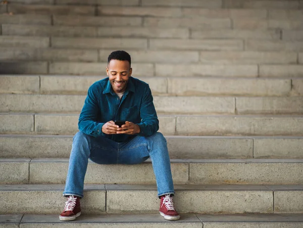 Sorridente Uomo Africano Americano Messaggistica Testo Utilizzando Smart Phone Sulle — Foto Stock