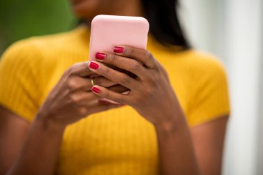 Açık havada cep telefonu kullanarak mesajlaşan Afrikalı Amerikalı kadınların elleri