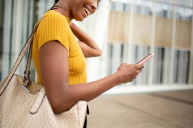 Neşeli Afro-Amerikan kadın profili cep telefonu kullanarak mesaj atıyor.
