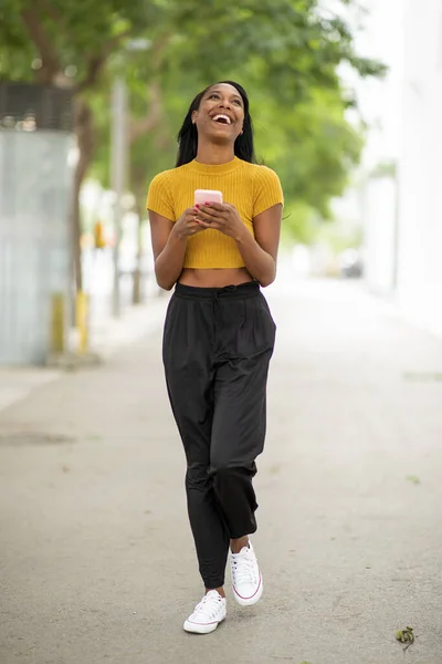 都会の通りで携帯電話を使いながら笑うスタイリッシュなアフリカ系アメリカ人女性 — ストック写真