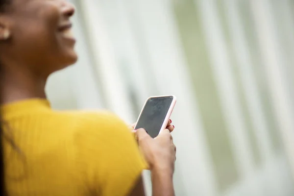 Over the shoulder shot of happy woman messaging using mobile phone