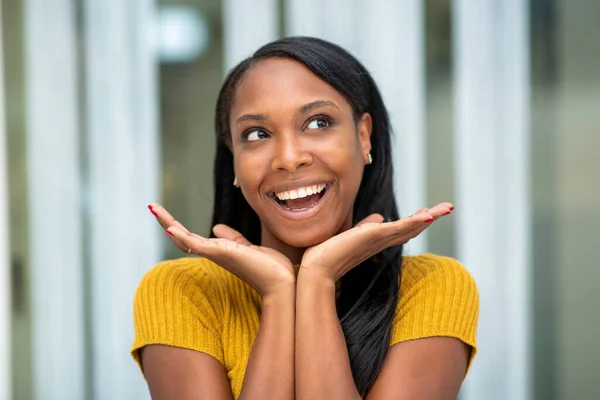 Excited african american woman holding palms under her chin and looking away