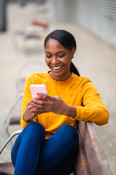 Leende Afrikansk Amerikansk Kvinna Meddelande Med Mobiltelefon Medan Sitter Utomhus — Stockfoto