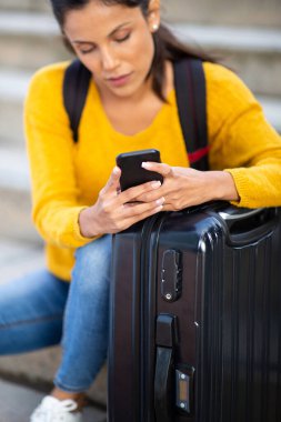 Cep telefonunu bavulla tutan genç bir kadının portresi 