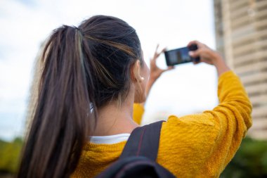 Kadın arkası cep telefonuyla fotoğraf çekiyor.